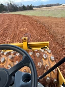 View from the cab compacting freshly tilled red clay field